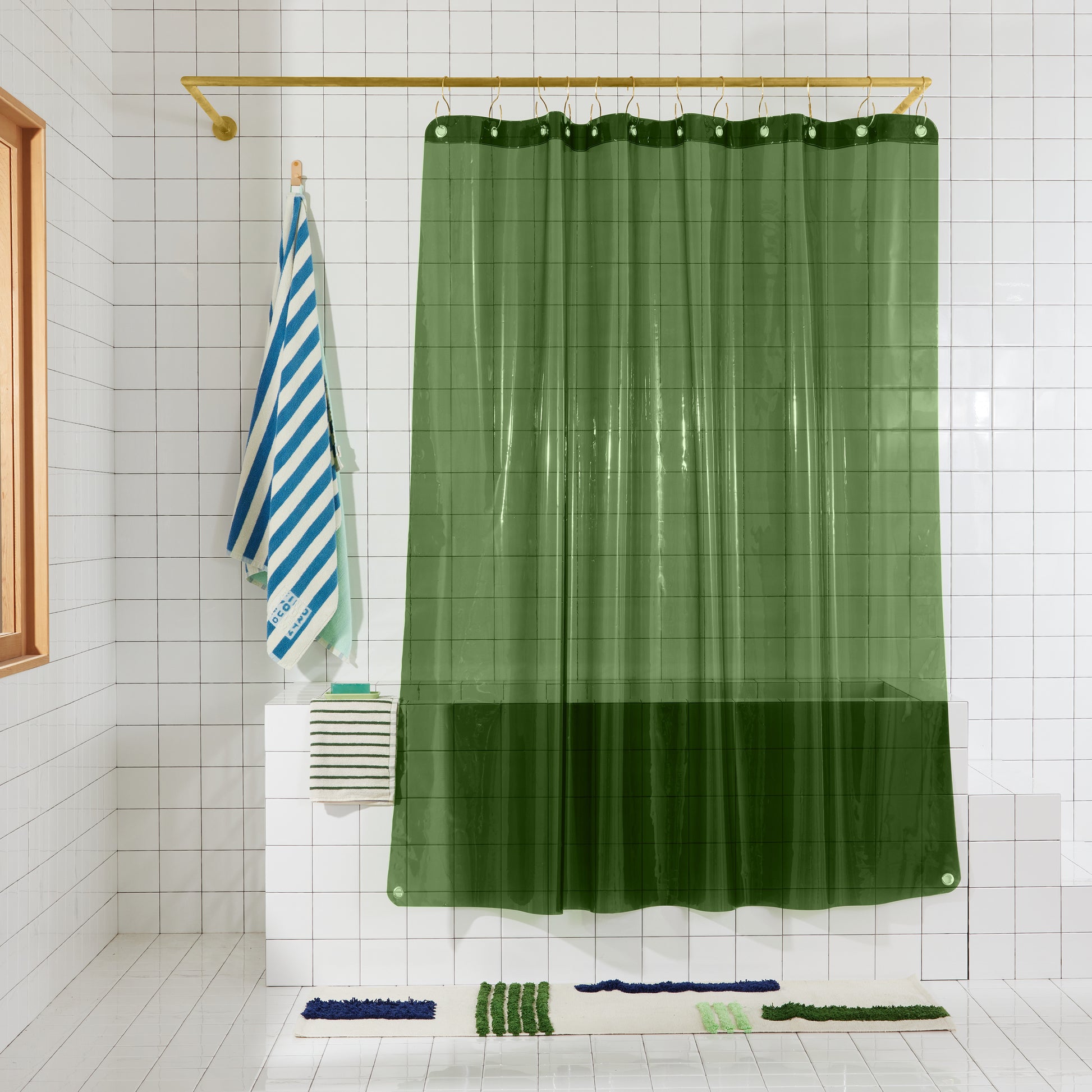 Sun shower curtain in pine hanging over bathtub styled in a white tiled bathroom 