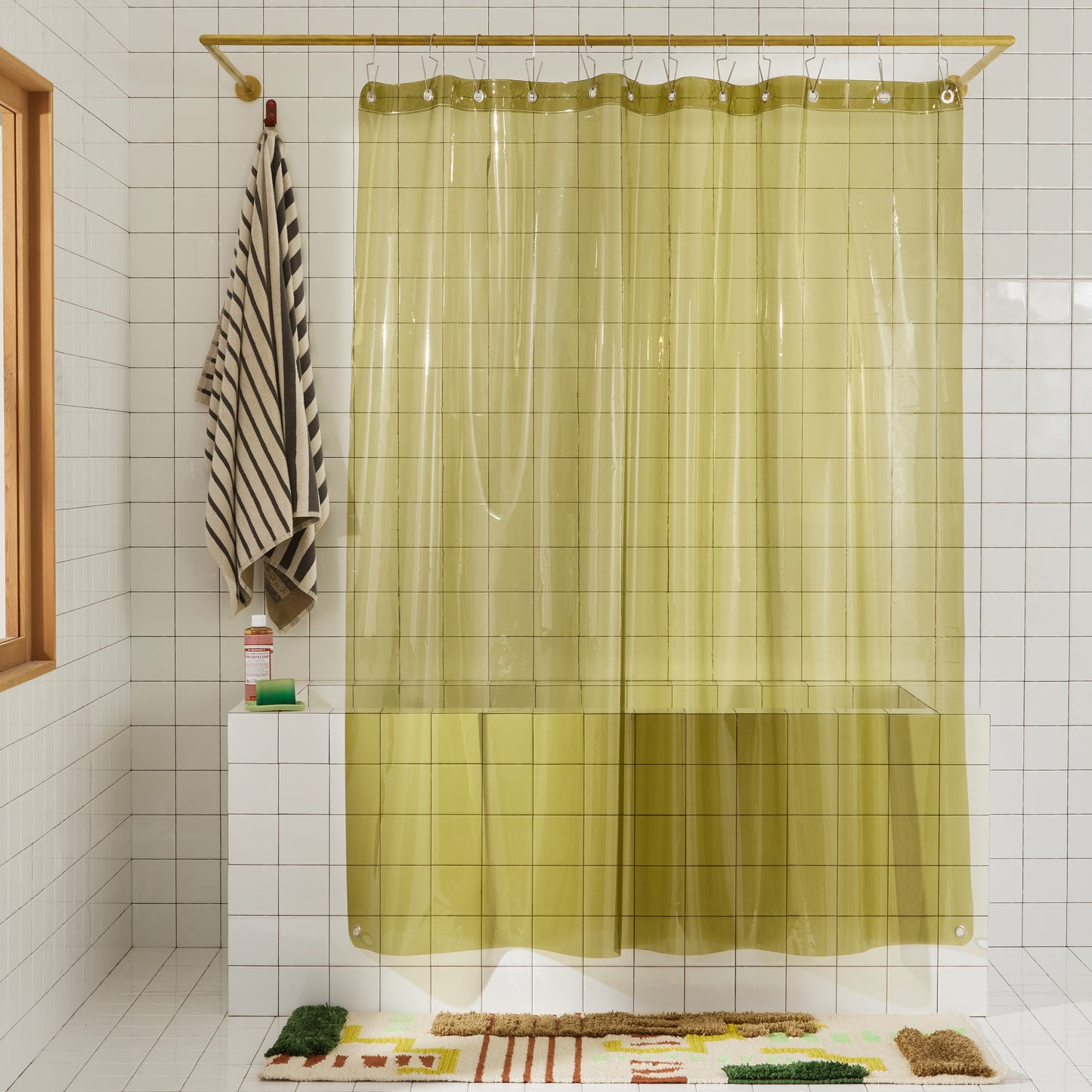 transparent olive green shower curtain hanging in white bathroom. 