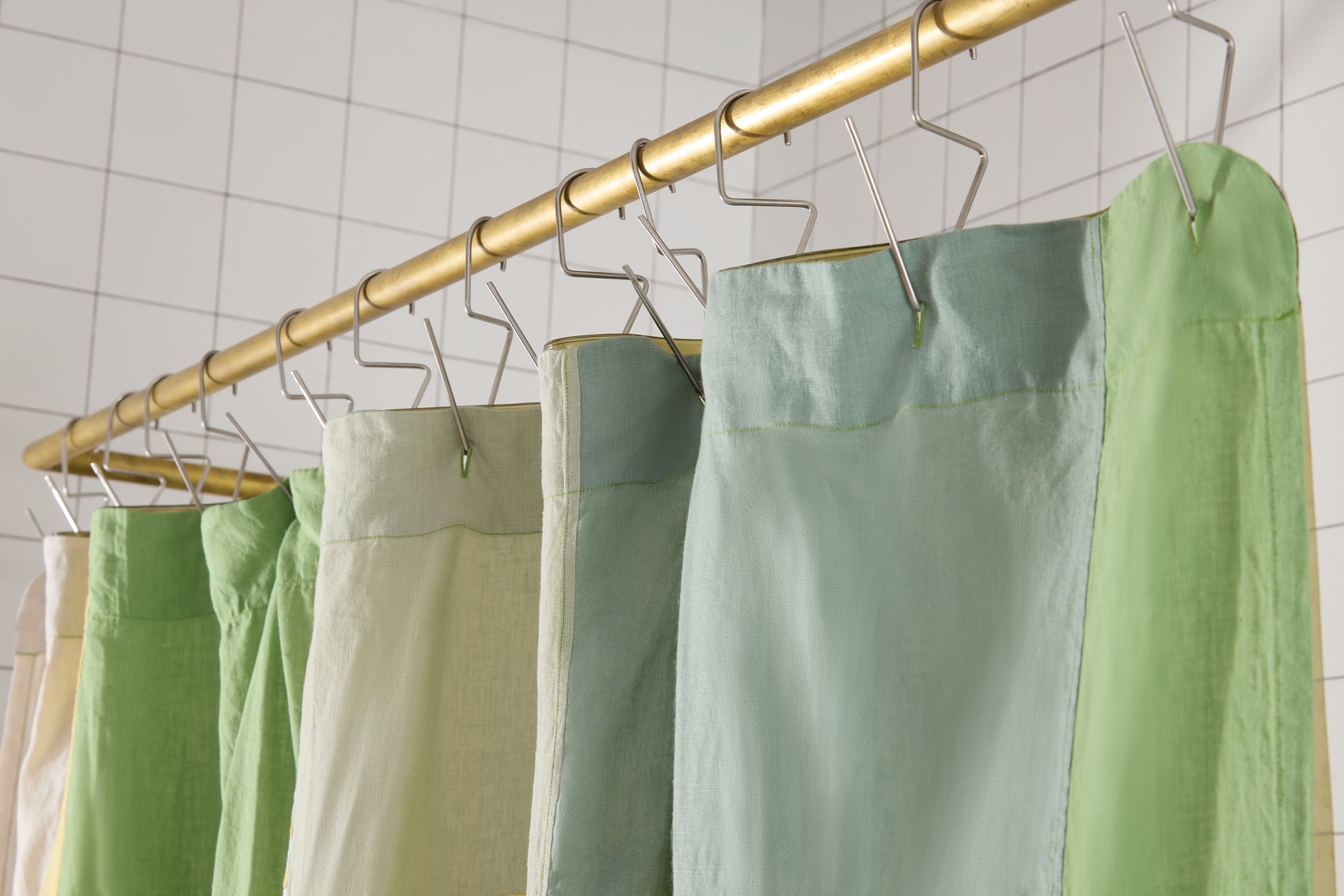 Green  shower curtain hanging on shoer rod off hooks