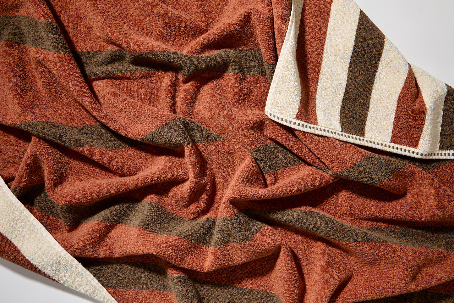 Close up of catalina bath sheet in chocolate, double sided with color to color stripes and a cream stripe running through the other side. 