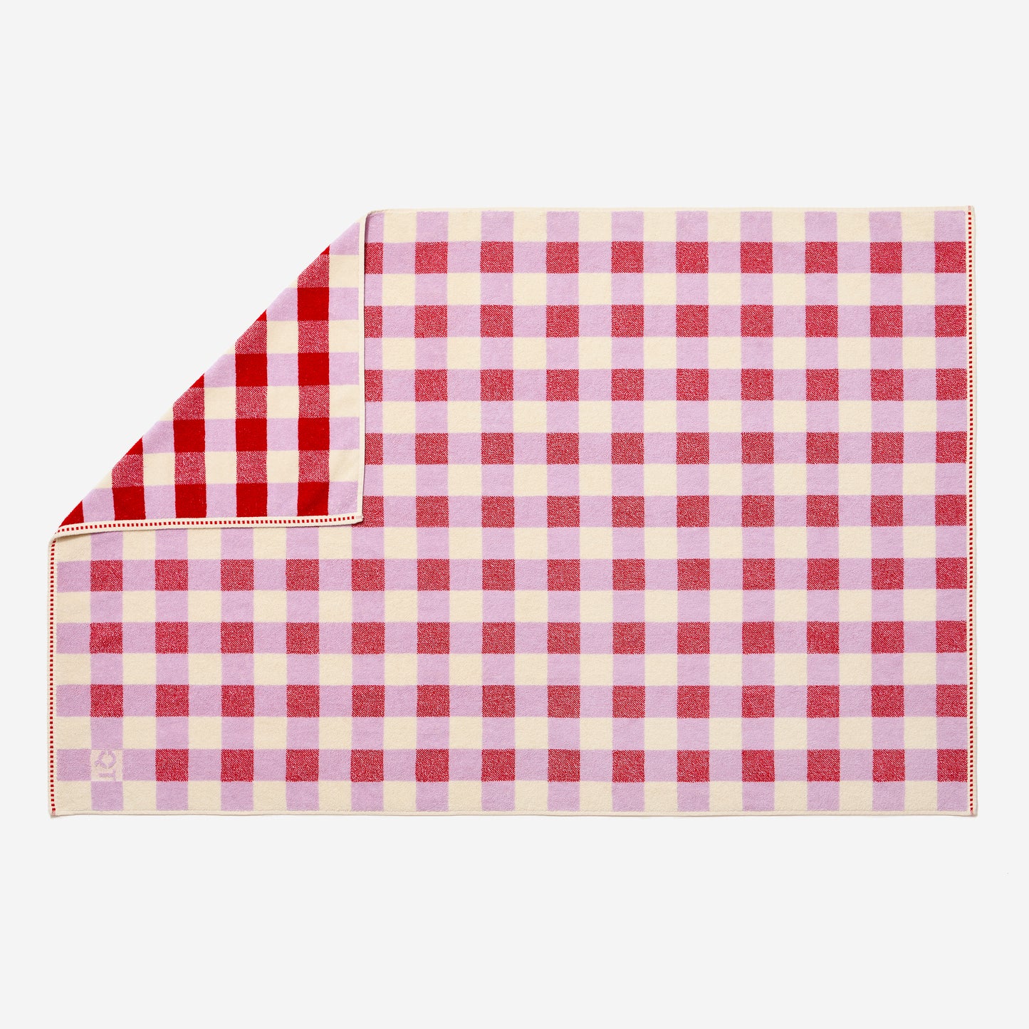 Full view of tam bath sheet in candy with checked pattern on both sides. One corner flipped up showing more saturated side. 