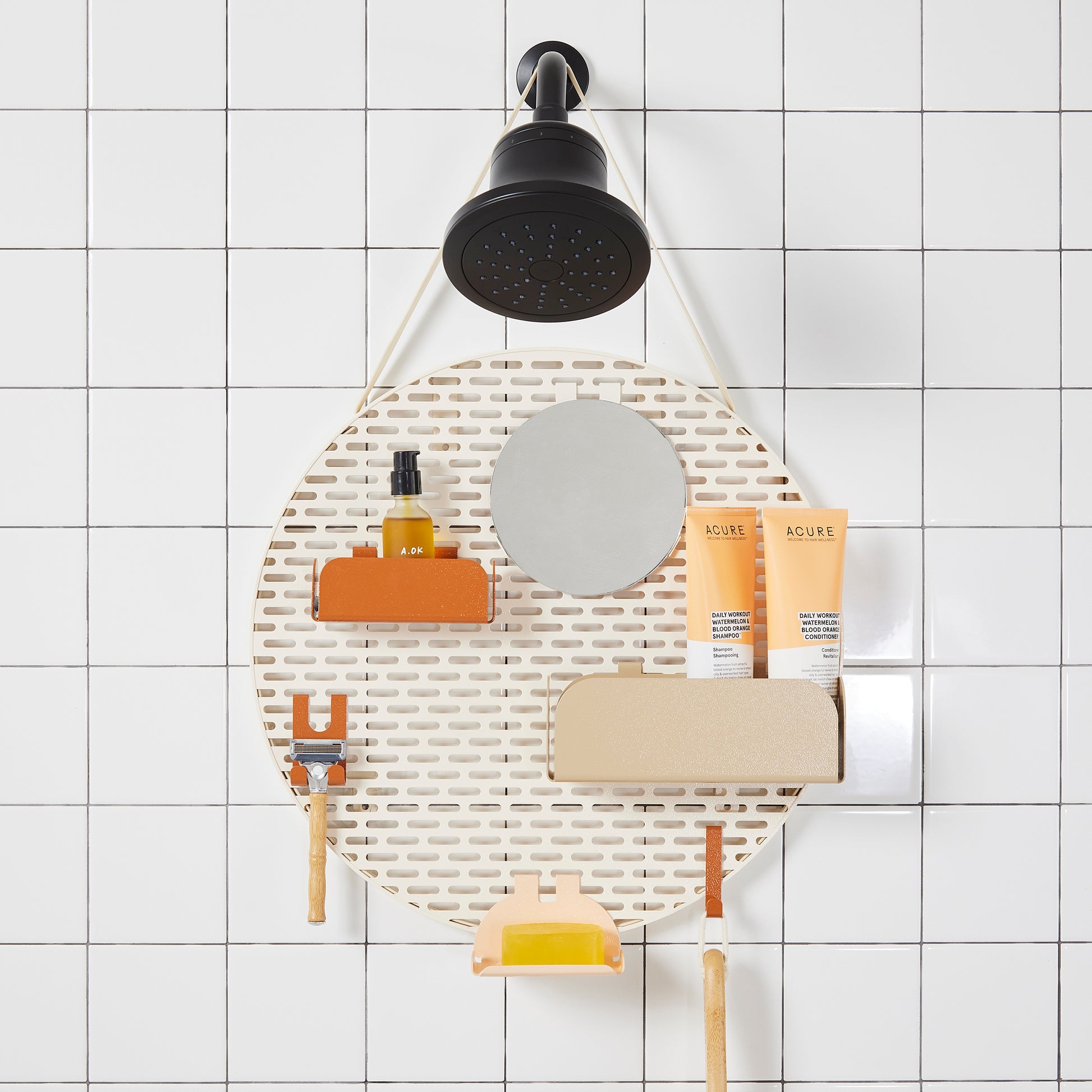 The spot modular shower organizer with shelving pieces arranged and holding products, hanging in a white tiled shower.