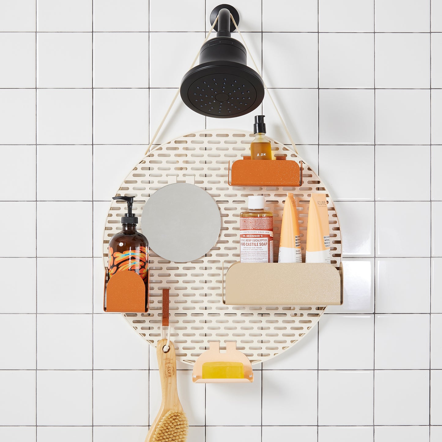 The spot modular shower organizer with shelving pieces arranged and holding products, hanging in a white tiled shower.